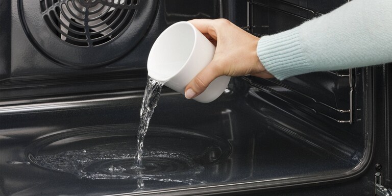 O persoana care toarna apa in cavitatea cuptorului