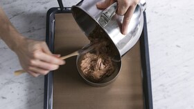 Un brutar care toarnă aluatul de tort într-o formă rotundă de tort