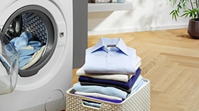 Washer dryer next to a pile of clothes