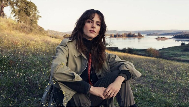 Femeie așezată pe iarbă în natură.